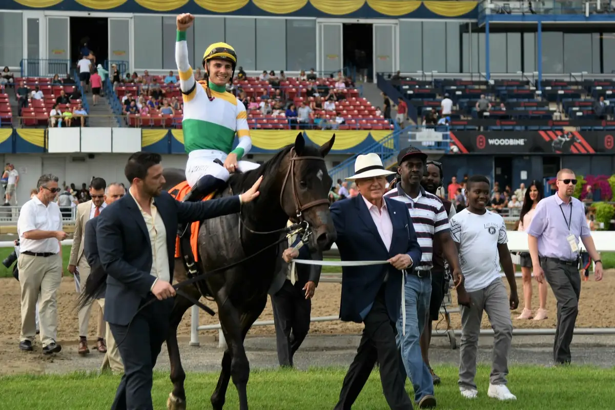 A jockey punching the air as the winner is led back past spectators at Woodbine